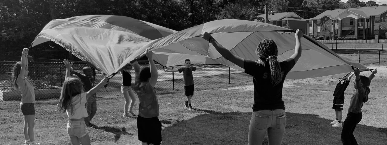 Volunteer plays parachute with a group of children.
