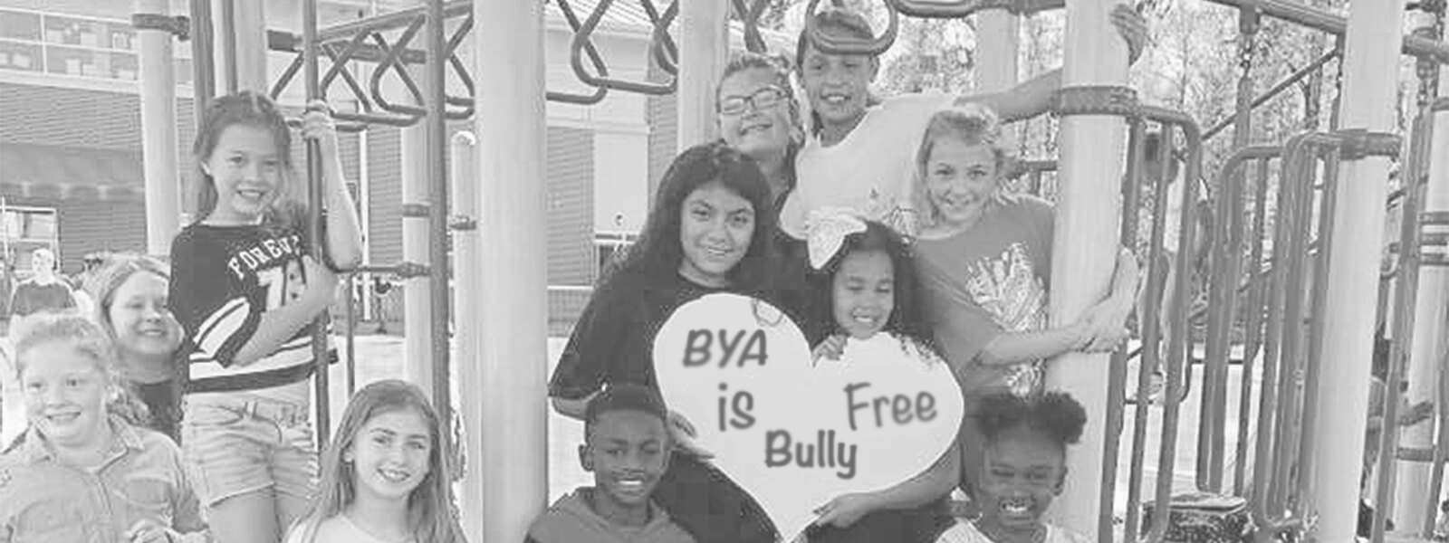 A group of children gathered around an anti-bullying sign.